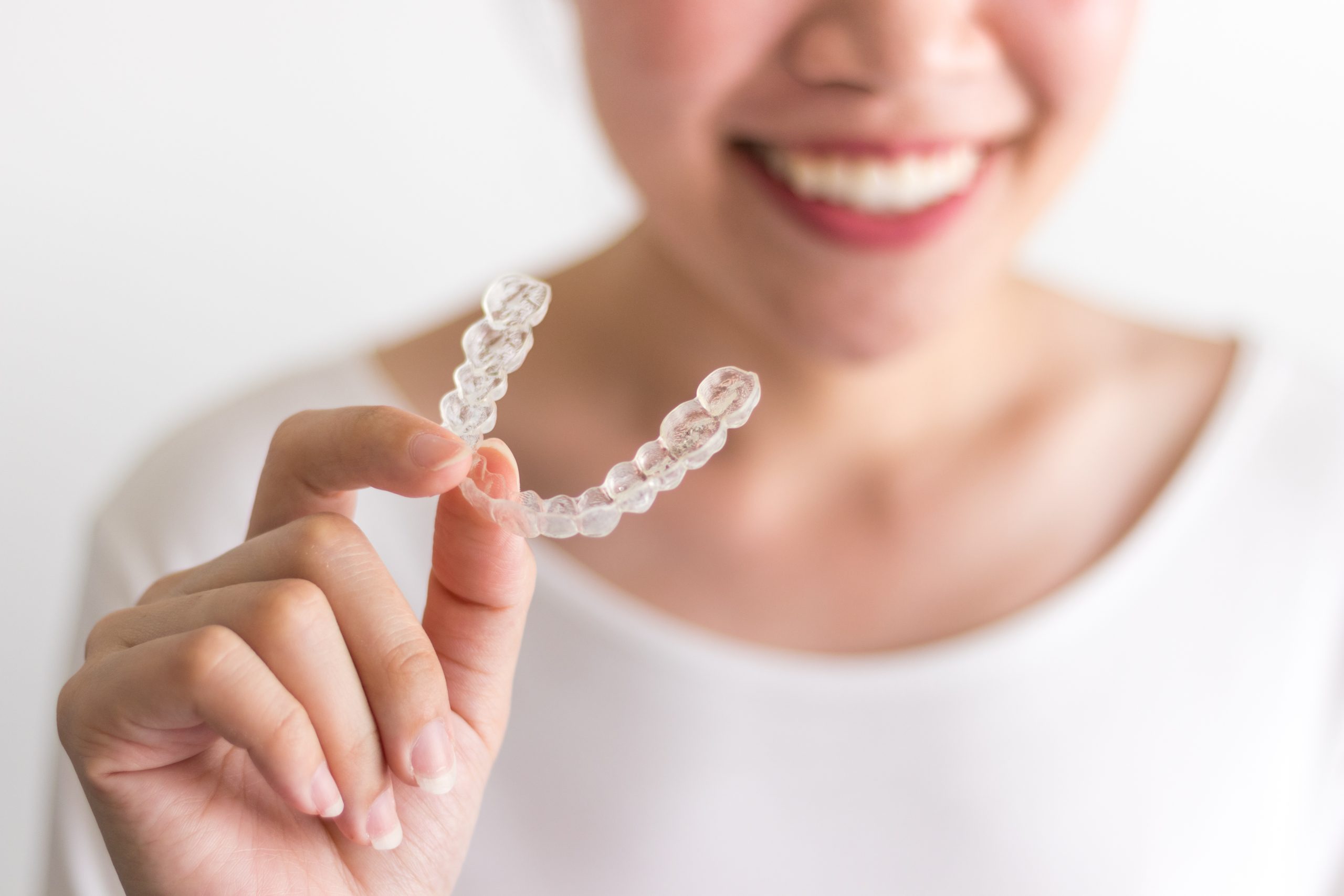 A Smiling Woman Holding Invisalign Or Invisible Braces, Orthodon