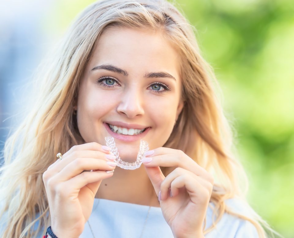Invisalign Orthodontics Concept Young Attractive Woman Holding Using Invisible Braces Or Trainer.