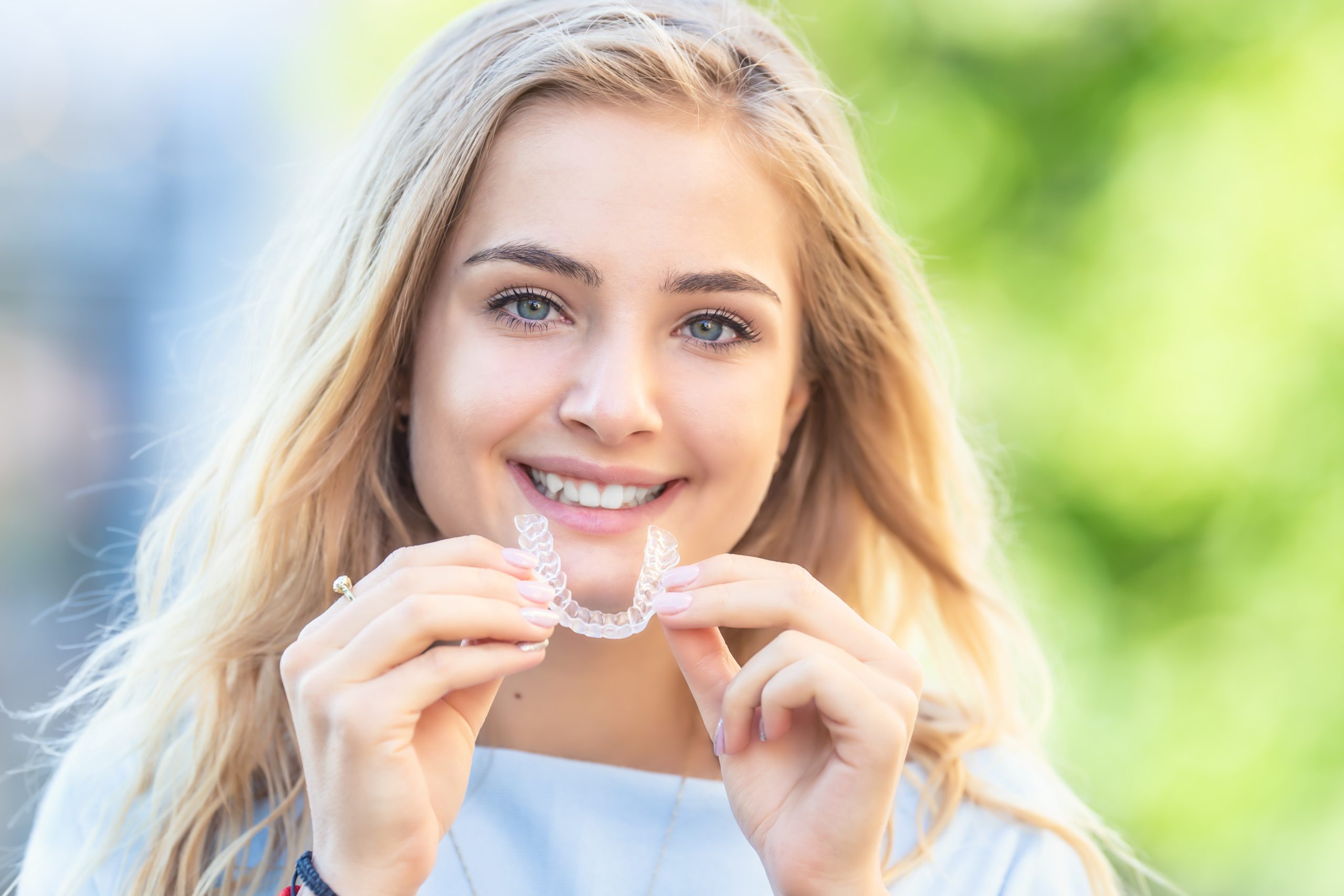 Invisalign Orthodontics Concept Young Attractive Woman Holding Using Invisible Braces Or Trainer.